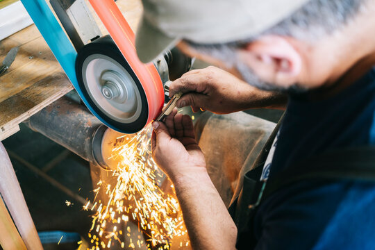 Craftsman grinding metal object forming bright sparks