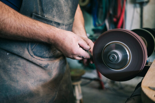 Craftsman sharpening knife blade on grinding wheel