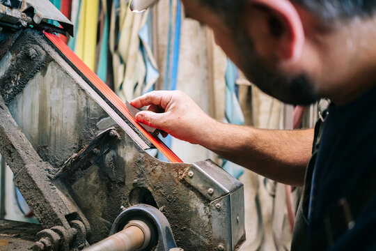 Craftsman grinding metal knife blade in workshop