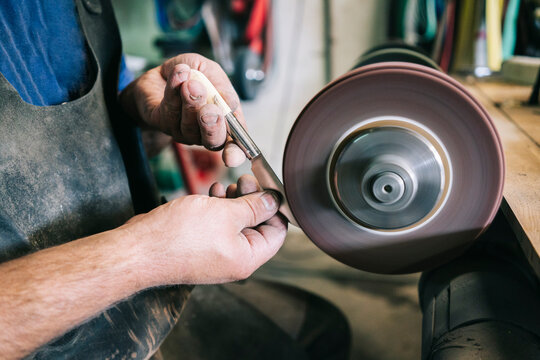 Craftsman sharpening knife blade on grinding wheel
