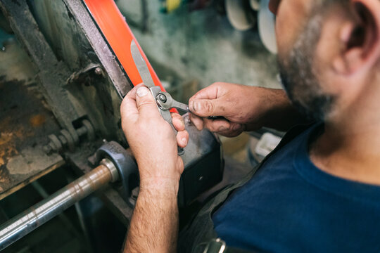 Craftsman grinding knife blade in workshop
