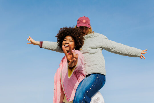 Joyful friends enjoying piggyback ride outdoors
