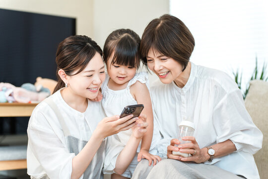 A three-generation family relaxing while looking at their smartphones (apps, videos, social media)