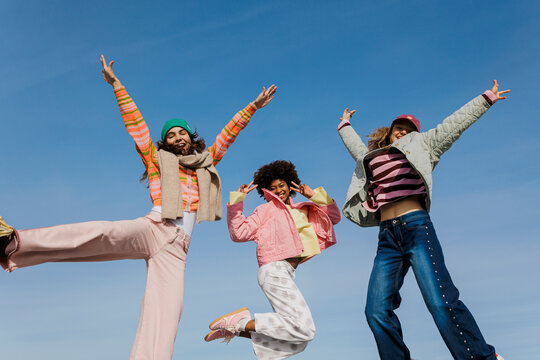 Friends jumping celebrating joy under blue sky