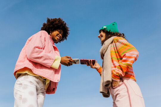 Friends sharing content using mobile phones outdoors