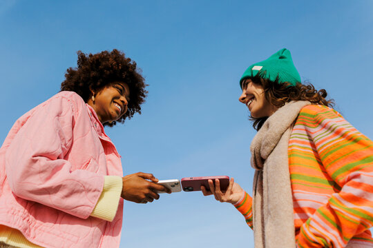 Teenagers sharing content on smartphones outdoors