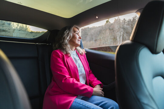 Woman looking out of the window from the back seat of a car