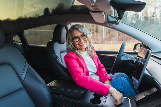 Smiling female driver in pink blazer behind the wheel