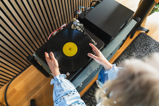 Close up of woman placing vinyl record on turntable at home