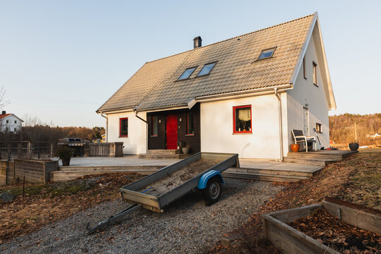 White modern house with trailer and garden beds in the countryside