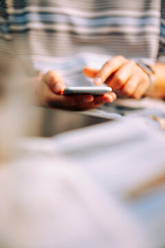 Hands of woman wearing blue, black, white striped t-shirt using phone