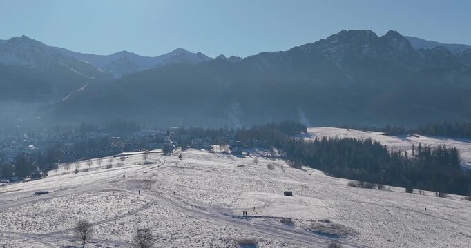 Winter aerial panorama of the Tatra Mountains and snow covered fields under clear blue sky