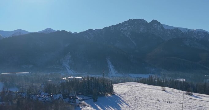 Winter aerial panorama of the Tatra Mountains and snow covered fields under clear blue sky