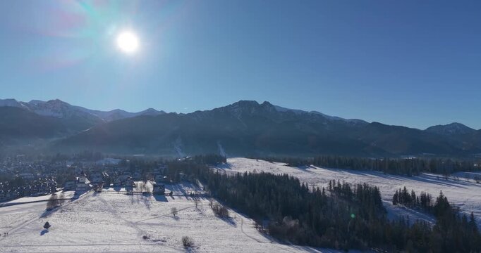 Winter aerial panorama of the Tatra Mountains and snow covered fields under clear blue sky