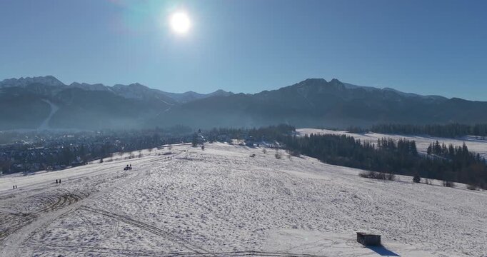 Winter aerial panorama of the Tatra Mountains and snow covered fields under clear blue sky