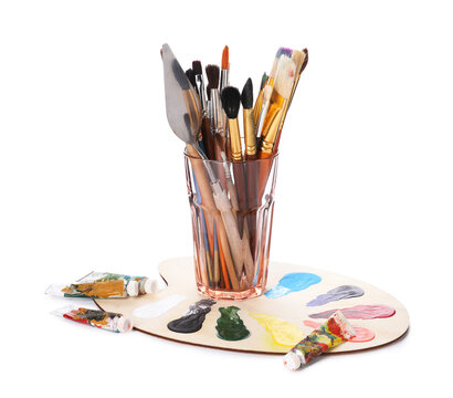 Paintbrushes with knife in glass, paints and palette isolated on white