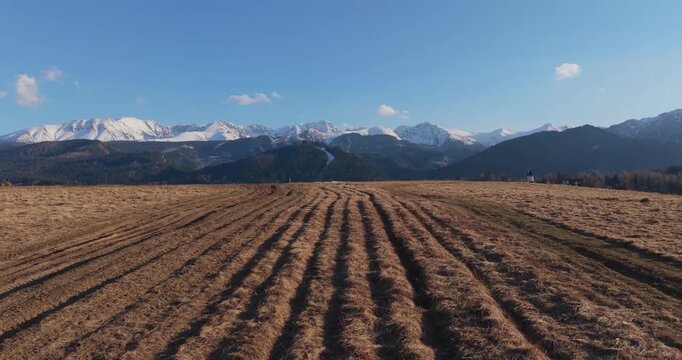 Spring aerial view of the Tatra Mountains with snowy peaks and meadow foreground