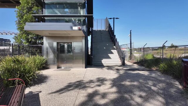Modern pedestrian footbridge access point in suburban Melbourne, Australia,&nbsp;featuring a lift elevator and concrete staircase, accessible passage over a railway line.&nbsp;Public transport infrastructure