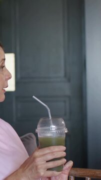 Vertical video: Camera shifting, hosts holding green drinks, recording into mic in studio, pink top