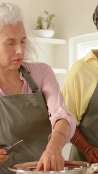 Vertical video: Slicing cook prompted by pot, peeling garlic at home kitchen for dinner in aprons