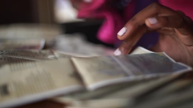 Girl flip a page and reading a textbook with stack of books on the table at home. Education concept.