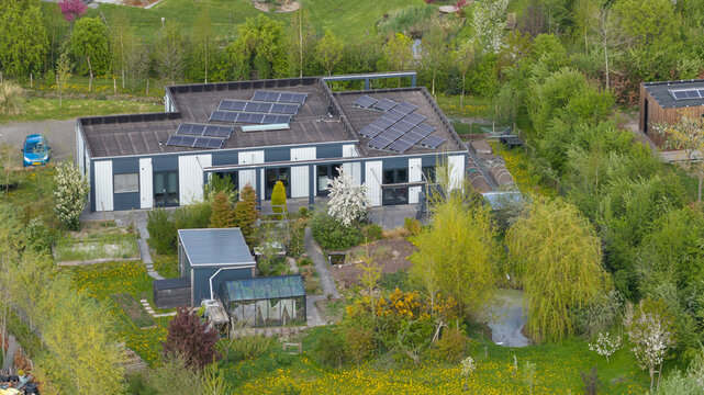 Aerial view of Ecodorp Bolderburen featuring sustainable houses with solar panels, lush gardens, and a greenhouse in Almere, Flevoland, Netherlands.