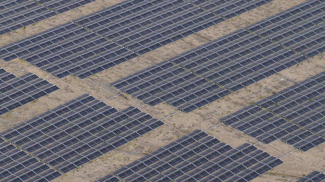 Aerial view of the Zonnepark Braambergen solar farm with rows of photovoltaic panels on sandy ground in Almere, Flevoland, Netherlands.