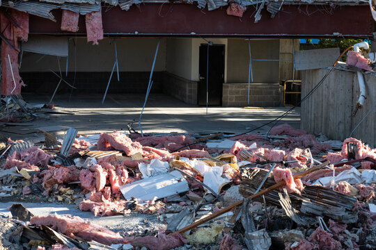 Old office building being torn down, walls and roof missing and I-beams exposed, as part of urban redevelopment, demolition in progress, pile of debris ready for removal

