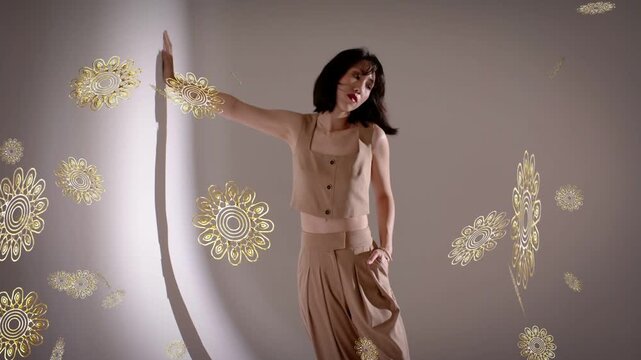 Model pressing palm on cyc holding pose, tilting for fashion with gold motifs floating around her