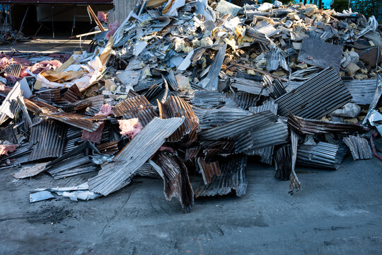 Pile of demolition debris, concrete, insulation, iron, corrugated sheet metal, old office building being demolished for urban redevelopment, sunny spring day
