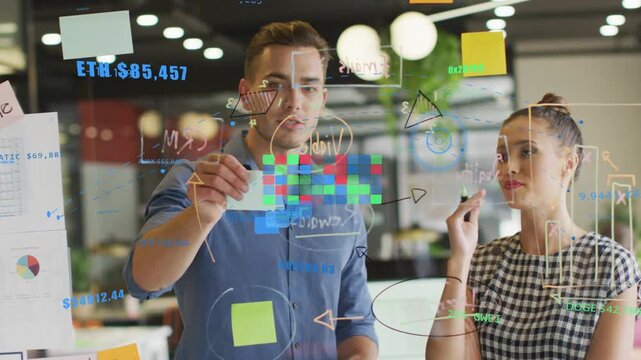 Woman writing on glass board, man placing sticky notes, both arranging color pixel grid for design