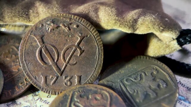 Detailed close up video of an antique 1731 VOC 1 duit coin featuring the classic VOC monogram and fox privy mark, captured from a slanted side angle.