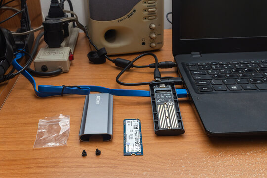 S&atilde;o Paulo, SP, Brazil - April 17th, 2026: Kingston M.2 2280 form factor NVMe SSD and an Exbom aluminum external enclosure next to a laptop.