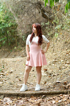 Joven latina con un vestido rosado corto, mujer bonita rodeada de naturaleza al aire libre. Concepto de moda y estilo de vida.