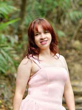 Chica guatemalteca con un vestido color rosado posando para la c&aacute;mara en un espacio abierto al aire libre, rodeado de naturaleza y vegetaci&oacute;n. Mujer joven y bonita con cabello casta&ntilde;o y ojos verdes.
