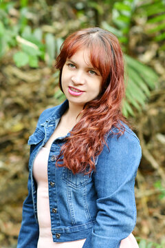 Mujer joven guatemalteca vestida con una chaqueta color azul y blusa rosada, chica linda con cabello casta&ntilde;o y ojos verde disfrutando de un espacio rodeado de naturaleza.