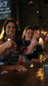 Vertical video: Camera shifting focus woman raising shot glass bar patrons toasting with gold stars