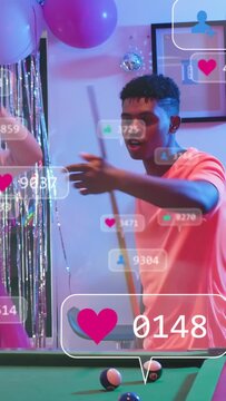 Vertical video: Man in coral tee leaning and shooting pool, causing floating likes on live stream