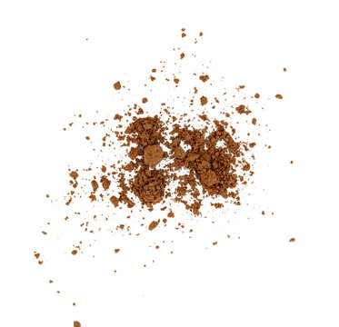 Scattered cocoa powder or coffee grounds. Overhead view of brown crushed powder texture with clumps and fine particles. Concept of food ingredients or cosmetic makeup.