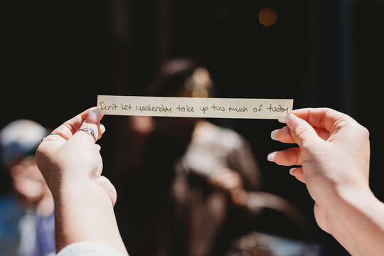 Hands holding a slip of paper witha quotw that says "Don't let yesterday take up too much of today"