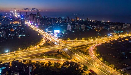 Fototapeta premium Aerial cityscape at dusk with illuminated highway interchange