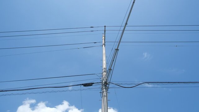 Following power lines into blue sky from moving car, utility wires converging and fading away