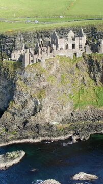 Aerial view of the medieval Dunluce Castle ruin perched on a dramatic cliff overlooking the Atlantic Ocean in Northern Ireland