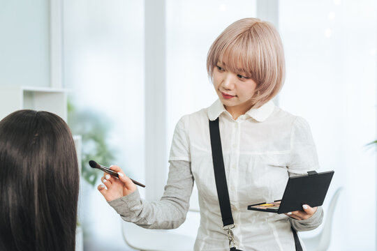 メイクするハイトーンヘアの女性スタッフ