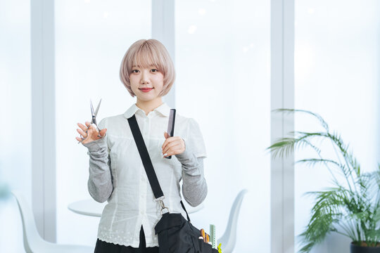 ヘアカット道具を持つハイトーンヘアの女性スタッフ