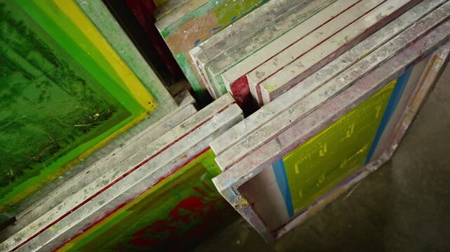 From above close up shot of multiple colorful printing frames stacked in storage rack at workshop with professional printing production environment
