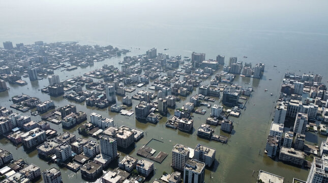 Aerial view of a sinking island city partially submerged in water, showcasing urban buildings surrounded by floodwaters under a hazy sky