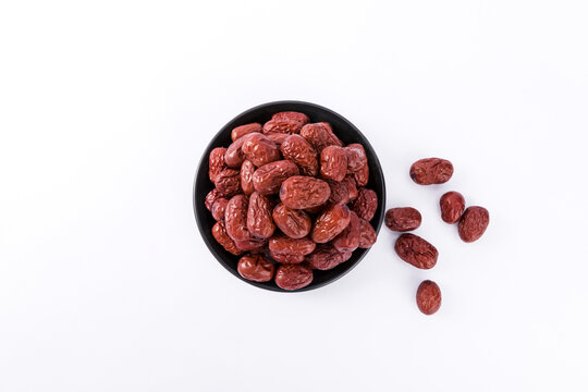 Dried red dates in black bowl on white background top view