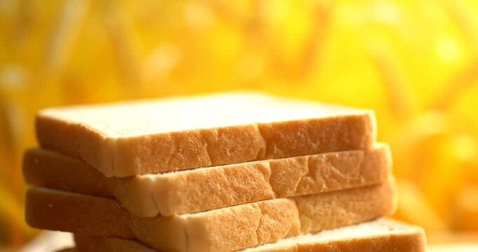 Freshly sliced bread stacked elegantly against a warm, blurred golden background