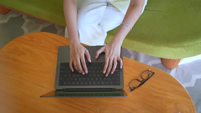 Asian Indonesian woman hands typing on laptop top view workspace